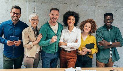 Diverse group of people smiling at the camera in an unspecified office setting.